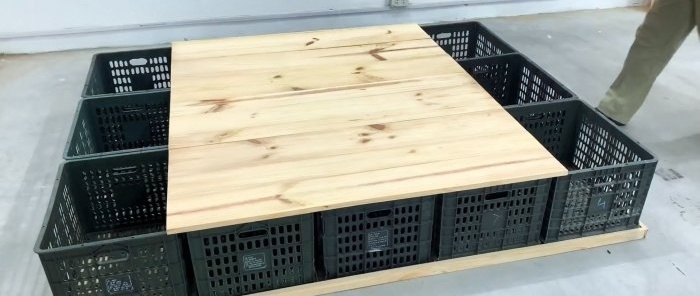 Cama feita de caixas plásticas para vegetais com vários espaços de armazenamento