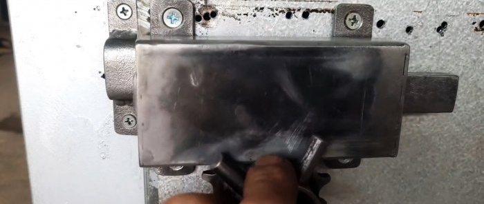 Pestillo de puerta con mando giratorio fabricado con materiales de desecho y piezas de motocicletas.